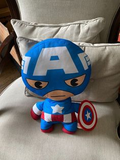 a stuffed toy sitting on top of a chair next to pillows and a pillow in the shape of captain america