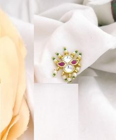 an image of a brooch with stones on it and a flower in the background