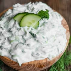 a wooden bowl filled with cucumber and sour cream