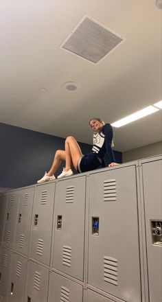 a woman sitting on top of lockers in a room