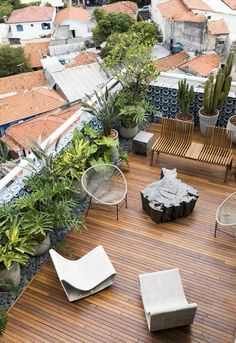 an outdoor deck with chairs and potted plants on the top, surrounded by wooden flooring