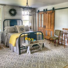 a bed room with a neatly made bed next to two chairs and a table in front of a window