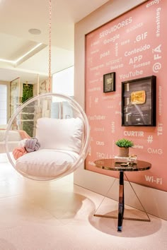 a living room with pink walls and a glass bubble chair hanging from it's ceiling