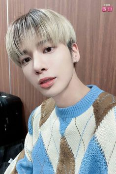 a man with blonde hair wearing a blue and white sweater