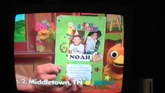 a person holding up a card with the name noah on it in front of a tv screen