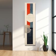 an abstract painting hangs on the wall next to a potted plant