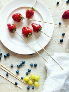 strawberries and grapes on a plate with toothpicks