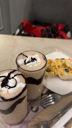 two drinks are sitting on a plate with silverware