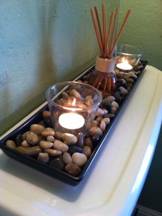 candles and rocks in a tray on top of a toilet