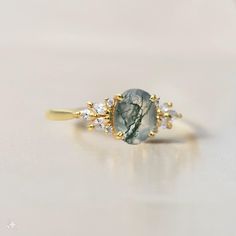 a gold ring with a green and white stone surrounded by small crystal stones on it