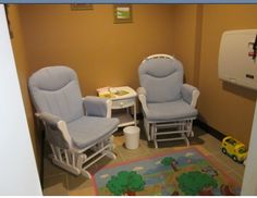 two rocking chairs and a table in a room with toys on the floor next to it