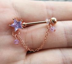 a person is holding a tiny nose piercing with purple stones on it's side