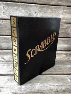 a black book sitting on top of a wooden table next to a white and brown wall