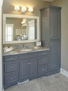 a bathroom with gray cabinets and marble counter tops