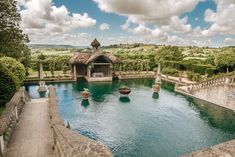 an outdoor swimming pool surrounded by lush green trees and greenery on a cloudy day