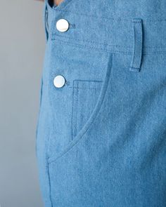 a person wearing blue pants with buttons on the side and one button in the pocket