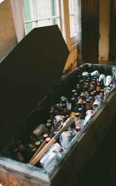 an open chest full of beer bottles in a room with wooden flooring and windows