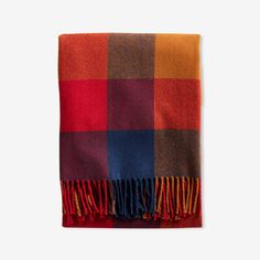 a red, orange and blue checkered blanket with fringes on the ends is shown