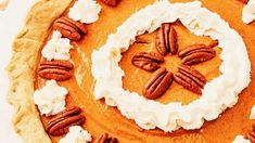 a pumpkin pie topped with whipped cream and pecans