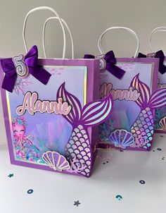 two purple bags with mermaid designs on them