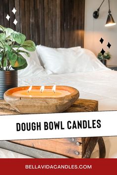 a candle is sitting on top of a wooden table in front of a white bed