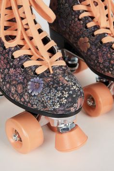 an orange skateboard with floral print and laces on the top, next to two roller blades