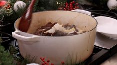 a pot filled with food sitting on top of a stove next to plates and christmas decorations