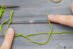 someone is working with yarn and scissors on a wooden surface that has been made into an ornament