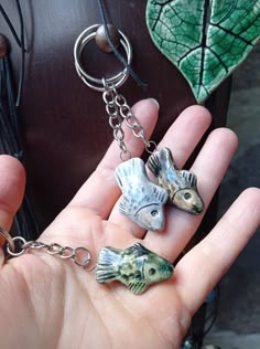 a person holding two fish charms in their hand