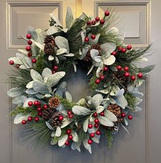 a christmas wreath with holly, berries and pine cones