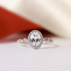 a close up view of a diamond ring on a white surface with a red background