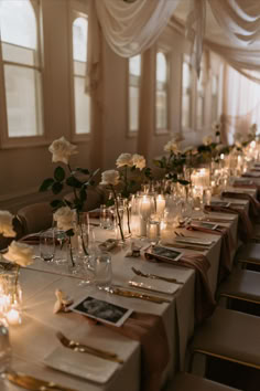 a long table is set with candles and flowers in vases on the tables are empty