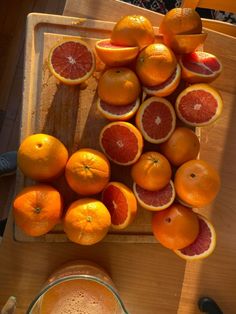 oranges and grapefruits on a cutting board next to a glass of juice