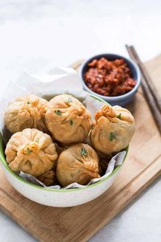 a bowl filled with dumplings next to a bowl of chili and chopsticks