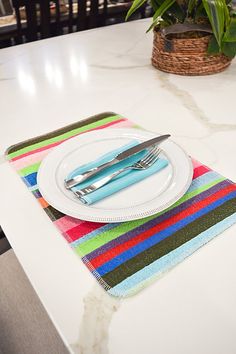 a place mat with a knife and fork on it next to a potted plant