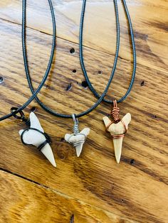 three necklaces on a wooden table with two different types of pendants hanging from them