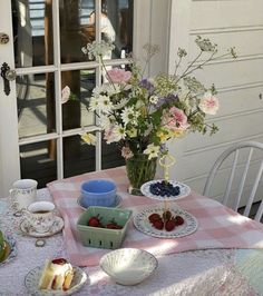 a table topped with plates and bowls filled with food next to a vase full of flowers