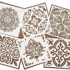 four stencils are shown on top of a wooden surface, one is white and the other has brown designs