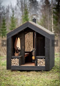 an outhouse with logs in the front and open doors on each side, sitting in a grassy field