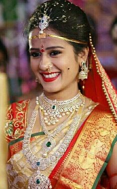 a woman in a red and gold sari smiles at the camera while wearing jewelry