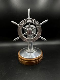 a metal spinning wheel on top of a wooden base with two spokes in the center