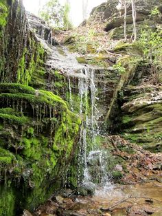 a small waterfall with moss growing on the rocks and water running down it's sides