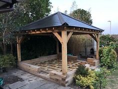 a wooden gazebo sitting in the middle of a garden