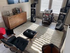 a living room filled with lots of furniture and sound equipment on top of a rug