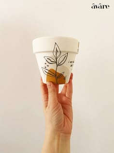 a hand holding up a cup with a plant on it's side and the words avare above it