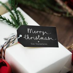 a gift wrapped in white paper with a merry christmas tag on it's side