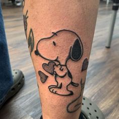 a man's leg with a tattoo of a dog holding a heart on it