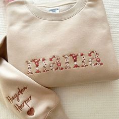 two personalized sweaters are laying next to each other on a bed with pink and white sheets