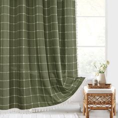 a green shower curtain hanging in front of a window with a white rug on the floor