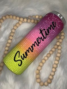 a pink, yellow and green water bottle with the word summer written on it next to beads